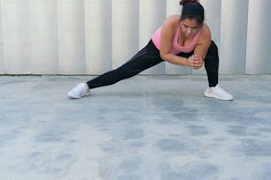 Latina athlete doing stretching exercise in park