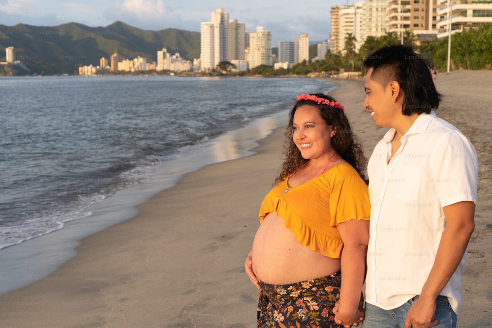 Young pregnant couple walking on the beach