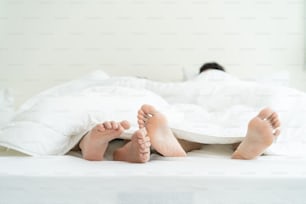 Nahaufnahme Füße eines männlichen schwulen Paares, das auf dem Bett liegt, mit Decke bedeckt. Romantischer Mann LQBTQ beginnt Vorspiel und Liebe machen, verbringen Sie morgens Freizeit zusammen im Schlafzimmer. Homosexuelle-LGBTQ-Konzept.