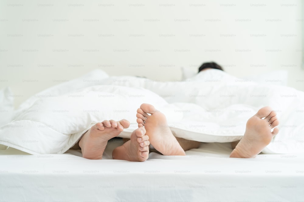 Primeros planos de los pies de una pareja gay masculina acostada en la cama, cúbralos con una manta. Hombre romántico LQBTQ que comienza los juegos preliminares y hace el amor, pasan el tiempo libre de la mañana juntos en el dormitorio. Concepto homosexual-LGBTQ.