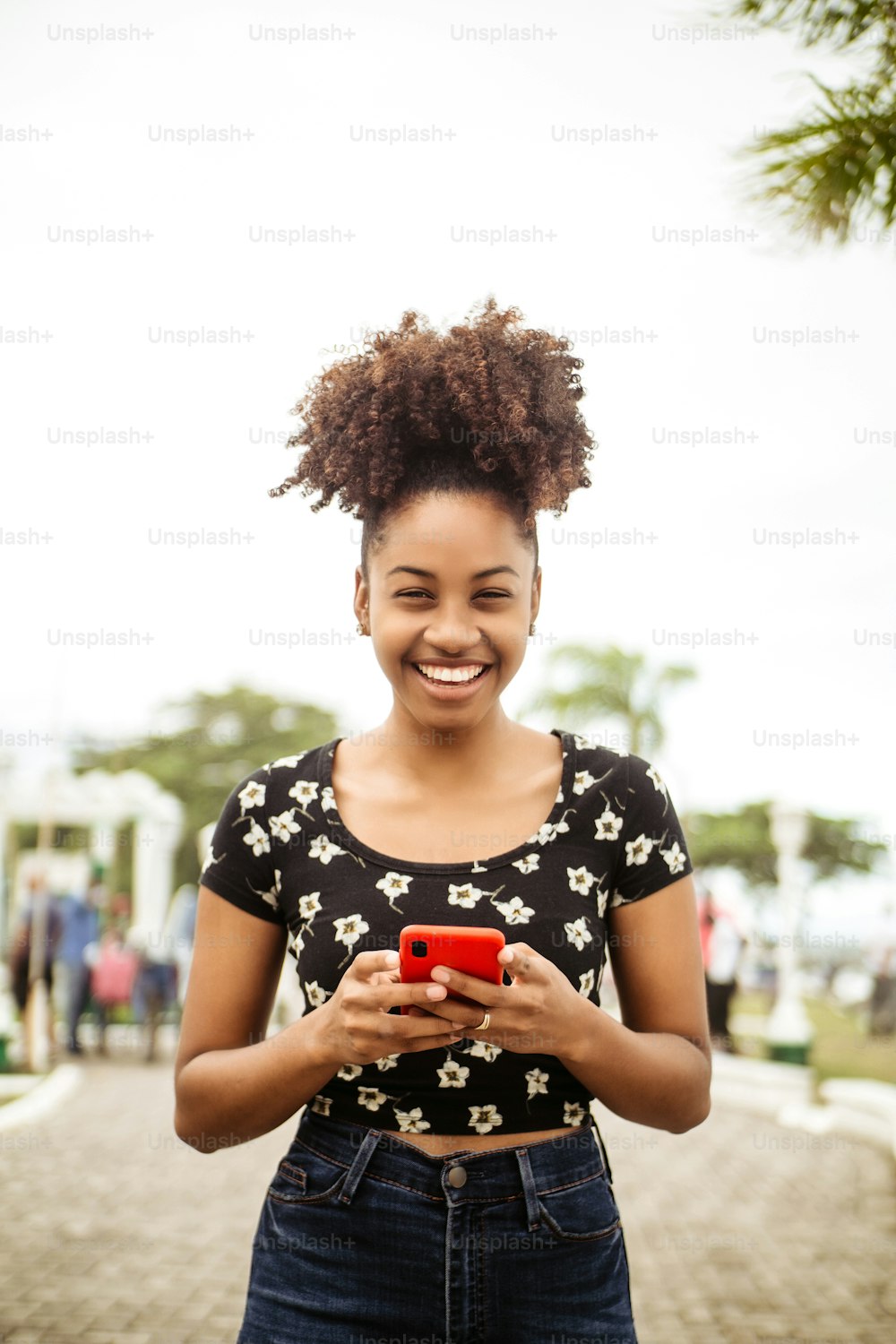 African woman laughing using Smartphone looking at camera.