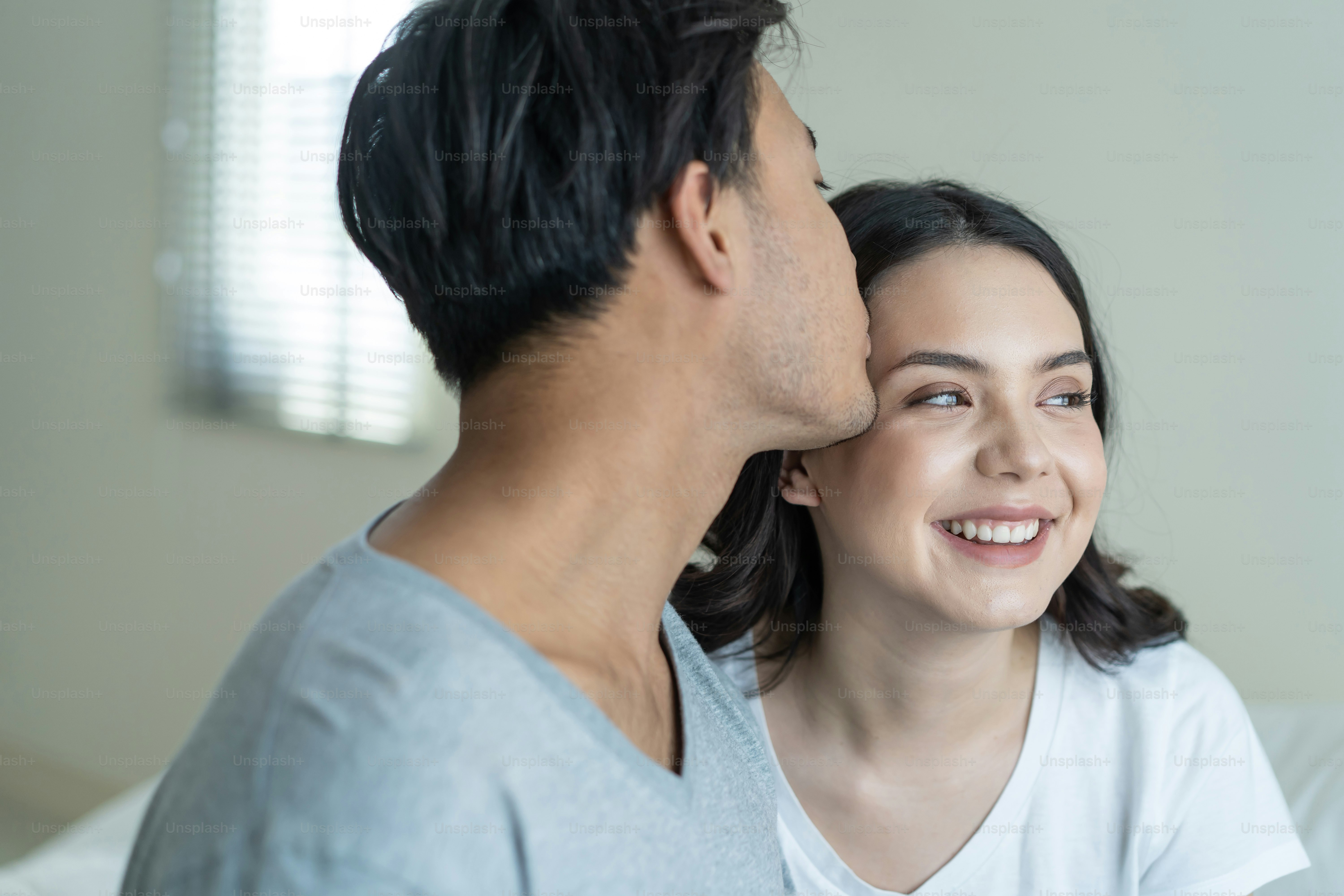 Asian attractive couple sitting together after wakeup in the morning. Young new marriage man and woman in pajamas feel happy and relax in early day after get up from bed in bedroom together at home.