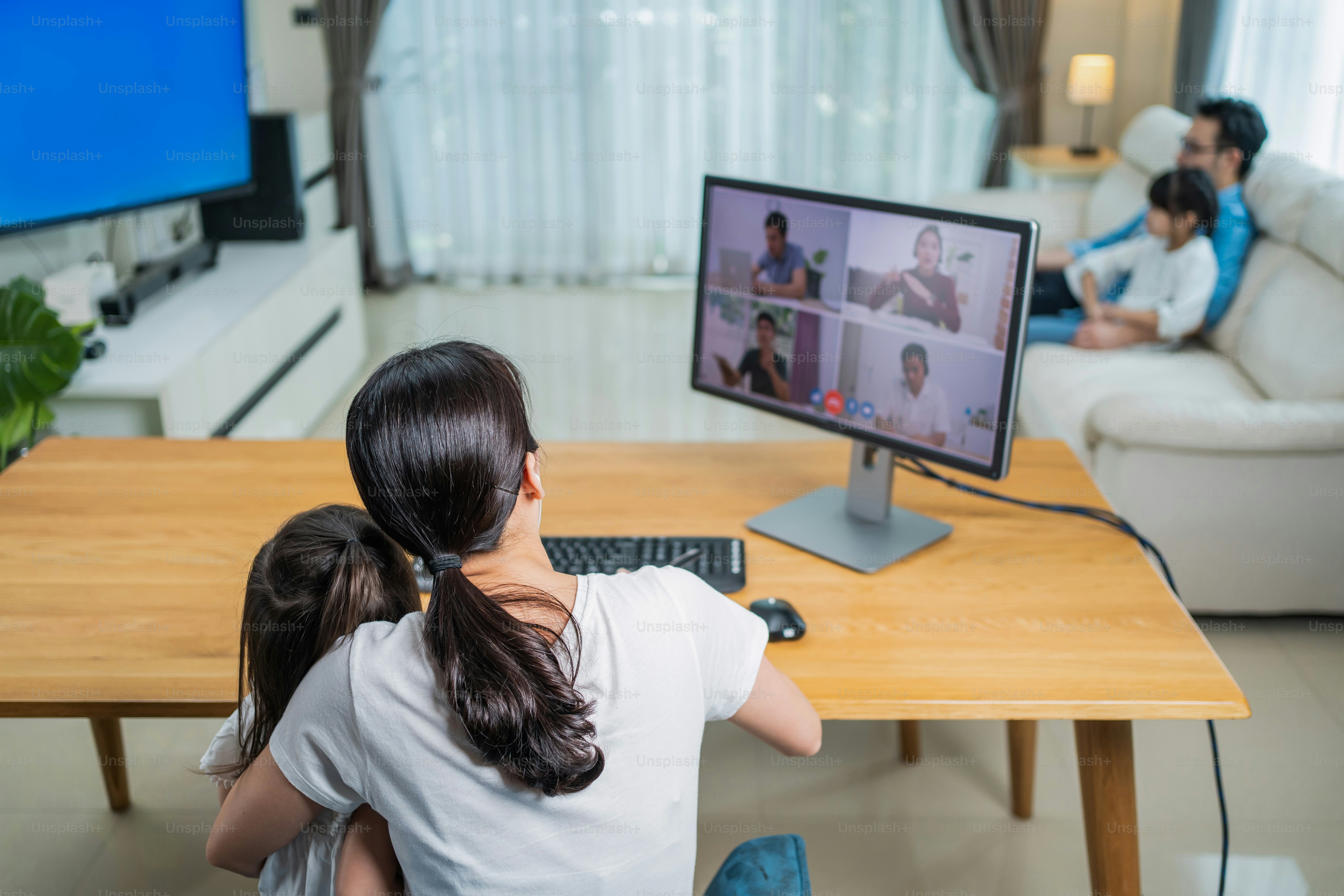 Pekerja lepas wanita Asia bekerja di rumah karena penguncian Covid-19 dengan anak perempuan dan keluarga. Ibu pengusaha wanita yang bekerja berbicara dengan tim kolega dalam konferensi panggilan video virtual online di rumah