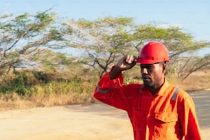 Afrikanischer mechanischer Mann setzt seinen Helm auf. Konzept des Ingenieurs oder Technikers.