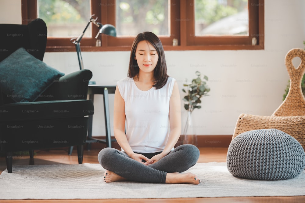 Happy Asian woman sporty attractive practicing meditation at home in living room