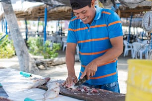 Pescador latino limpando peixe no mercado local