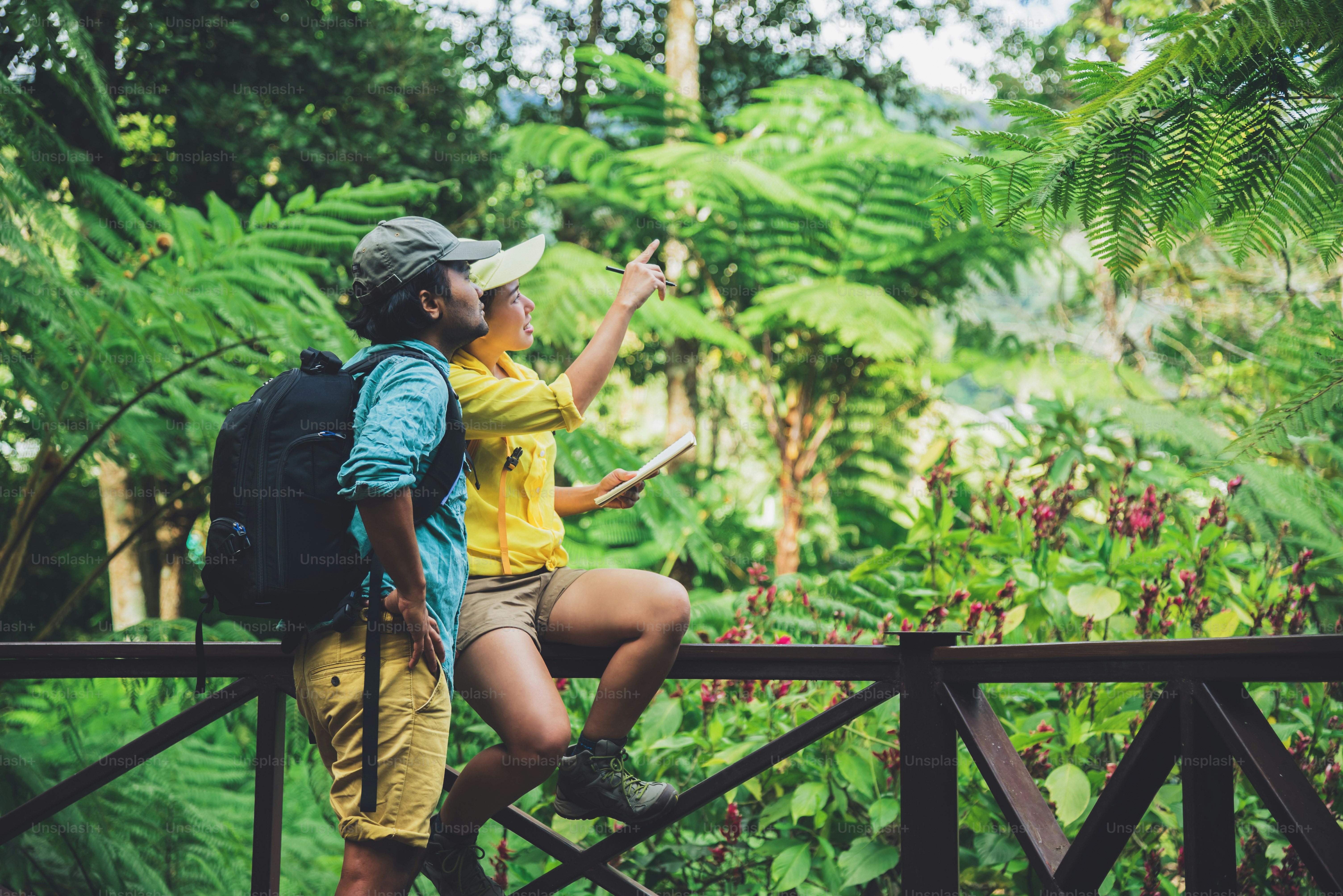 Asian couple travel nature walking relax and studying nature in the fores.