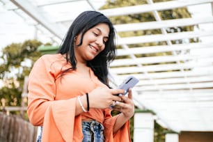 Smiling Latin American young woman using a mobile phone.