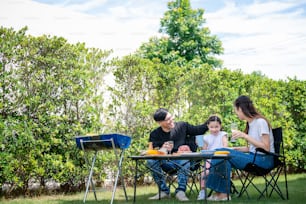 Happy asian family parents enjoying picnic day with daughter outdoor  on sunny day