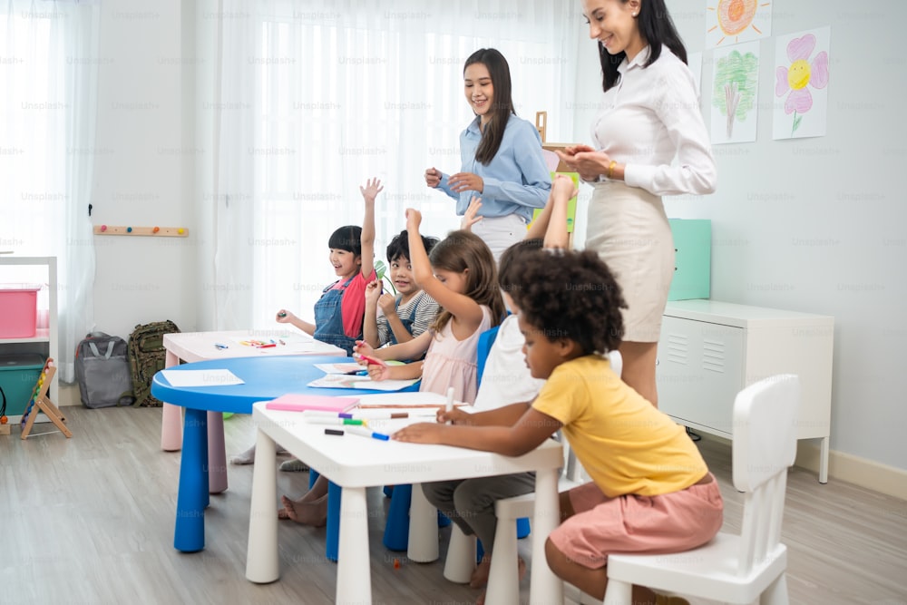 Bella giovane donna asiatica insegnante che insegna una lezione al bambino a scuola. Il maestro istruttore delle donne attraenti spiega ed educa lo studente dei bambini con un'attività divertente in classe all'asilo prescolare