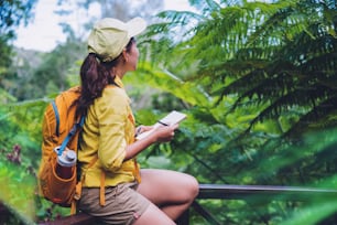 The young woman who is sitting writing, recording and studying the nature of the forest.