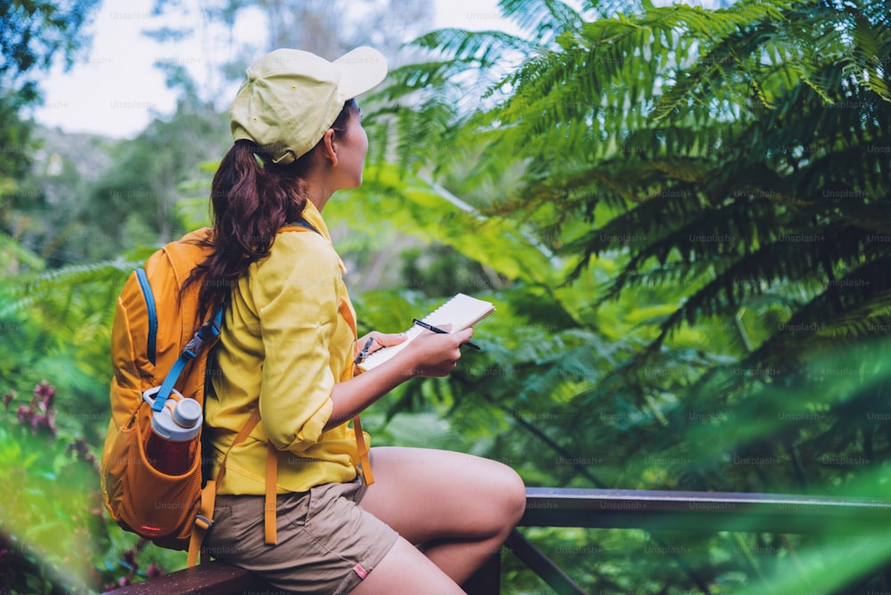 The young woman who is sitting writing, recording and studying the nature of the forest.