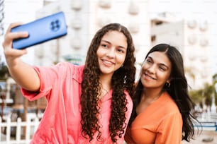 Two friends latin american women with brackets taking a photo over street.