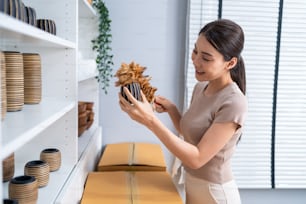 Asian beautiful woman clean vase goods order for customer from shelf. Young attractive business girl working to preparing parcel boxes checking ecommerce shipping online retail to sell at home store.