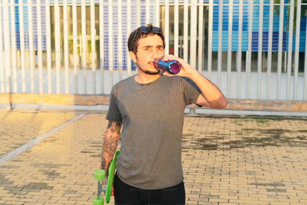 Young man drinking water after skateboarding