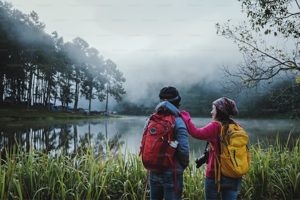 Couple lovers travel beatiful nature panorama view of Pang Ung lake in the mist at sunrise, Mae Hong Son province, Thailand.