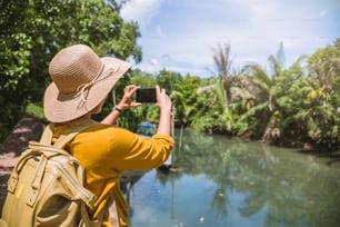 Asian woman travel nature. Travel relax. Using Mobile phone Take a boat photo beautiful nature at tha pom-klong-song-nam. Krabi, Travel Thailand.