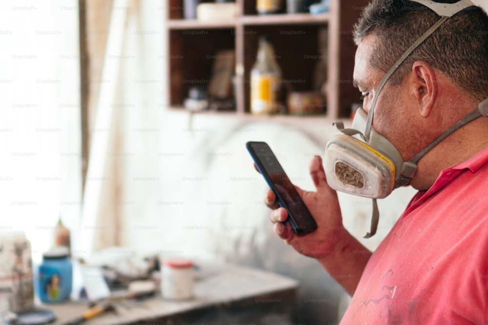 Carpenter in a workshop checking his cell phone