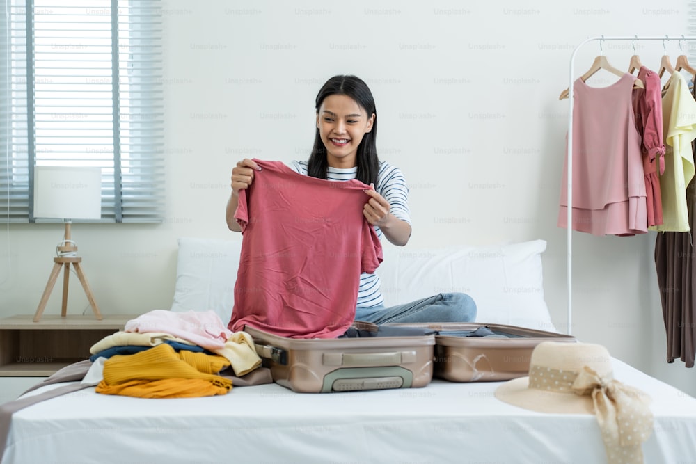 Crop woman packing suitcase on bed - a Royalty Free Stock Photo