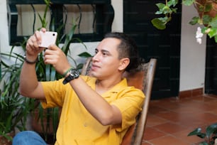Mann setzt sich, um ein Selfie mit seinem Handy zu Hause zu machen