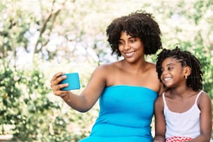 Portrait d’une femme afro-américaine avec une petite fille souriante et joyeuse prenant un selfie. concept technologique.