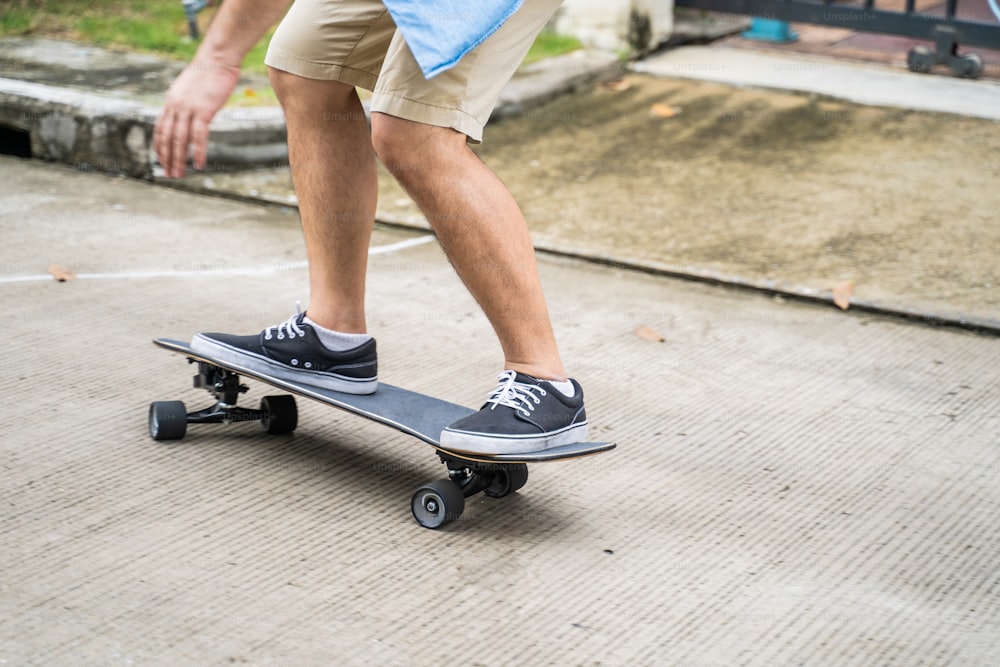 Close up a legs of active Asian hipster guy ride Surf Skate Board on street in front of his house. Extreme sport man skater enjoy leisure activity in free time surfing for health care and well being.