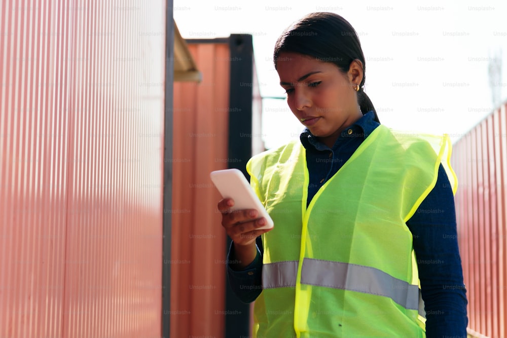 Portrait of a woman checking her cell phone while working in a distribution warehouse.