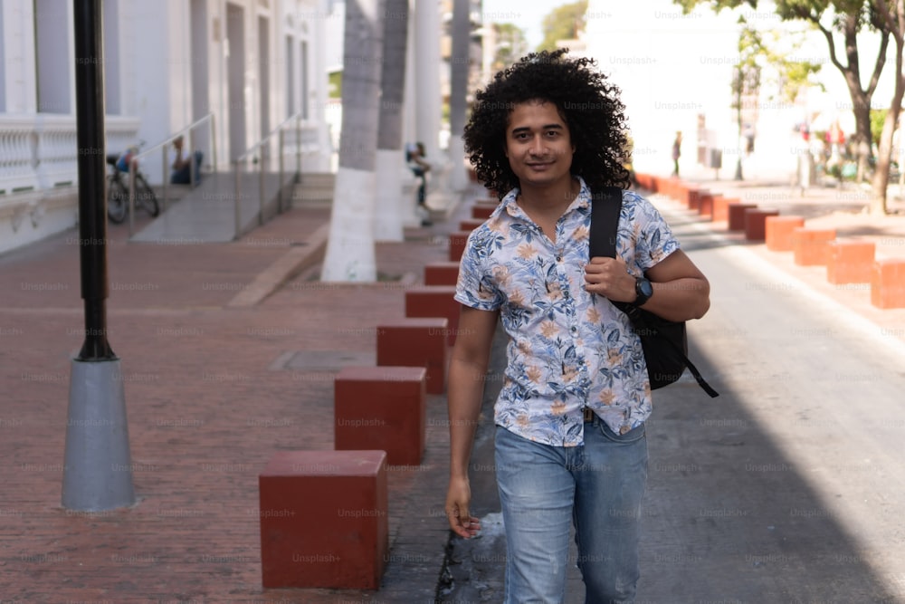 Studente universitario afroamericano, con zaino, che cammina per strada.