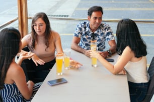 A group of smiling young people sharing in a bar.