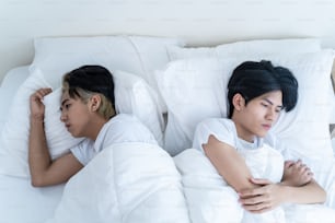 Asian male LQBTQ lying down on bed with painful after fight argument. Handsome romantic man gay couple feeling heartbroken for quarrel conflict and sleep in bedroom. Family problem-separation concept.