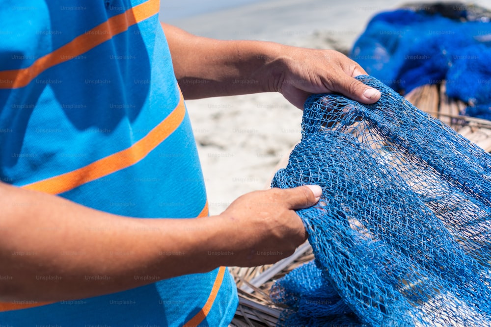 close-up de um par de mãos de pescador segurando uma rede de pesca.