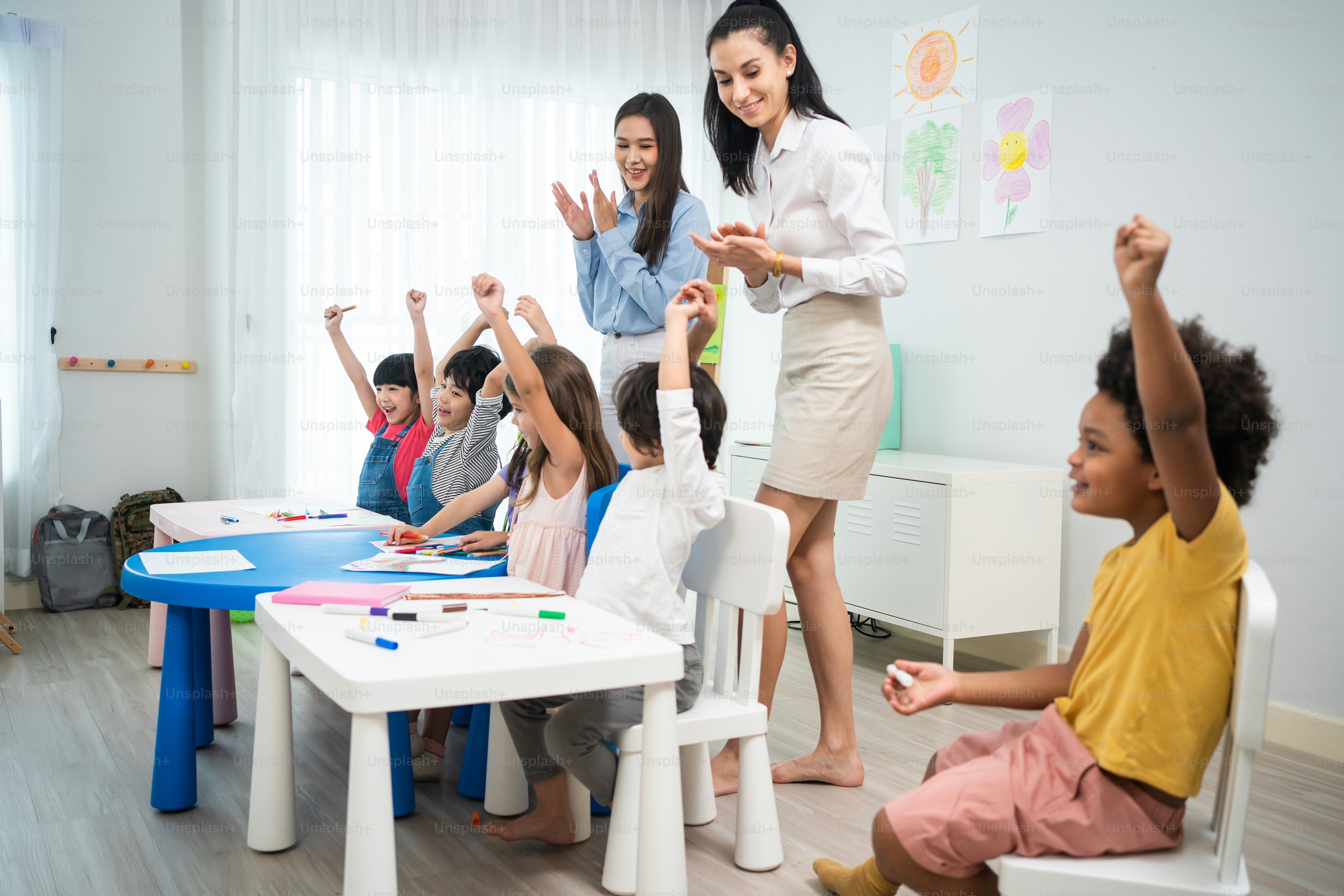Caucasian beautiful young woman teacher teaching art to kids at school. Attractive Instructor master female explain and educate drawing and painting with student kindergarten pre school in classroom.