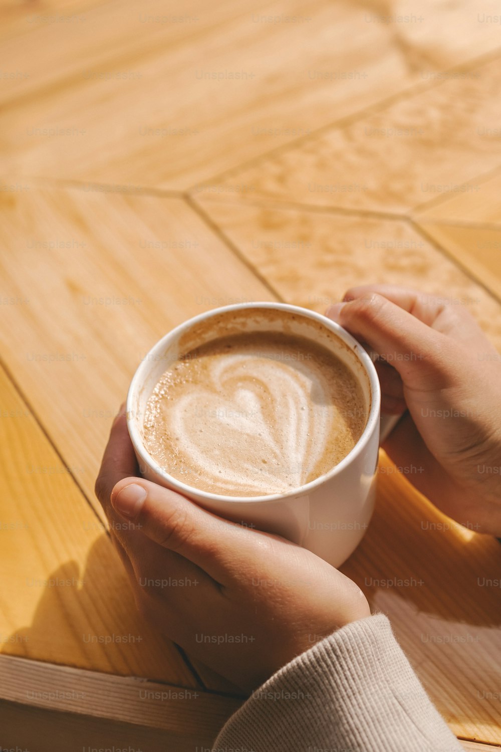 uma pessoa segurando uma xícara de café em cima de uma mesa de madeira