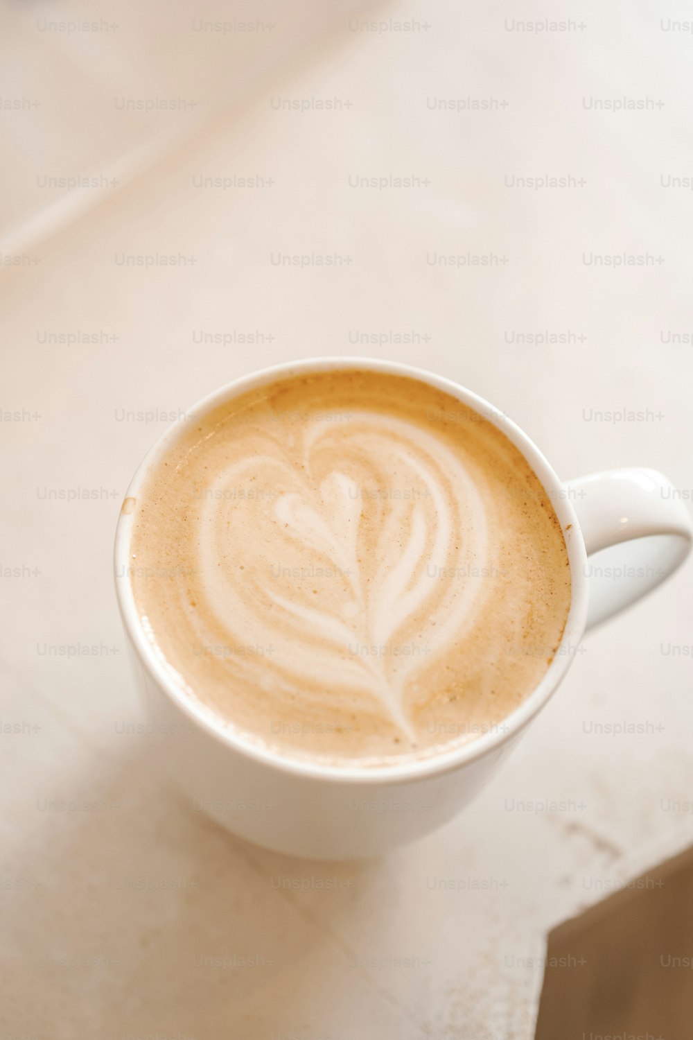 un cappuccino con un disegno a foglia in una tazza bianca