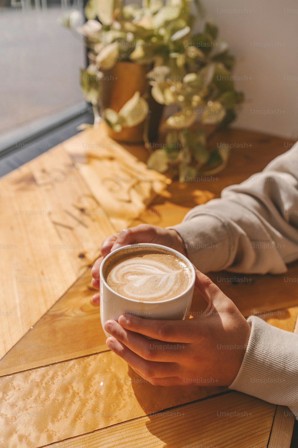 uma pessoa sentada em uma mesa segurando uma xícara de café