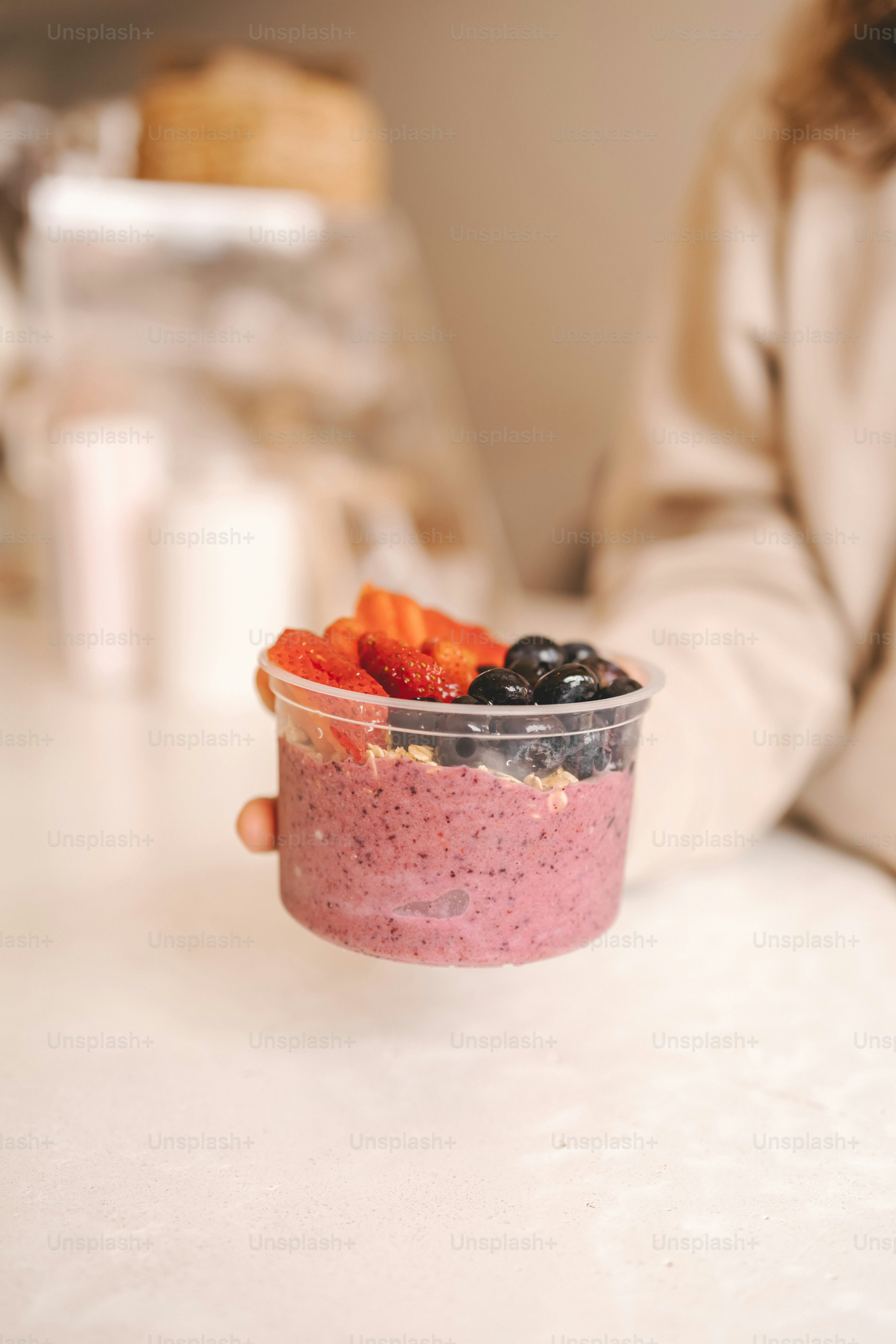 a person holding a cup of food on a table