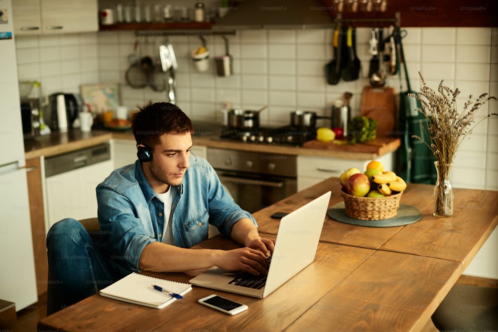 Young man using laptop and typing an e-mail while working at home.