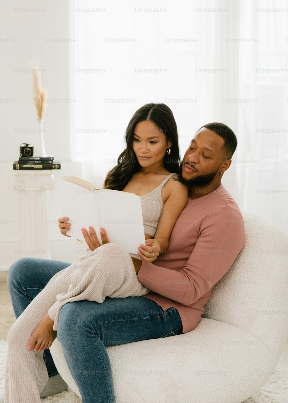 a man and a woman sitting on a couch reading a book
