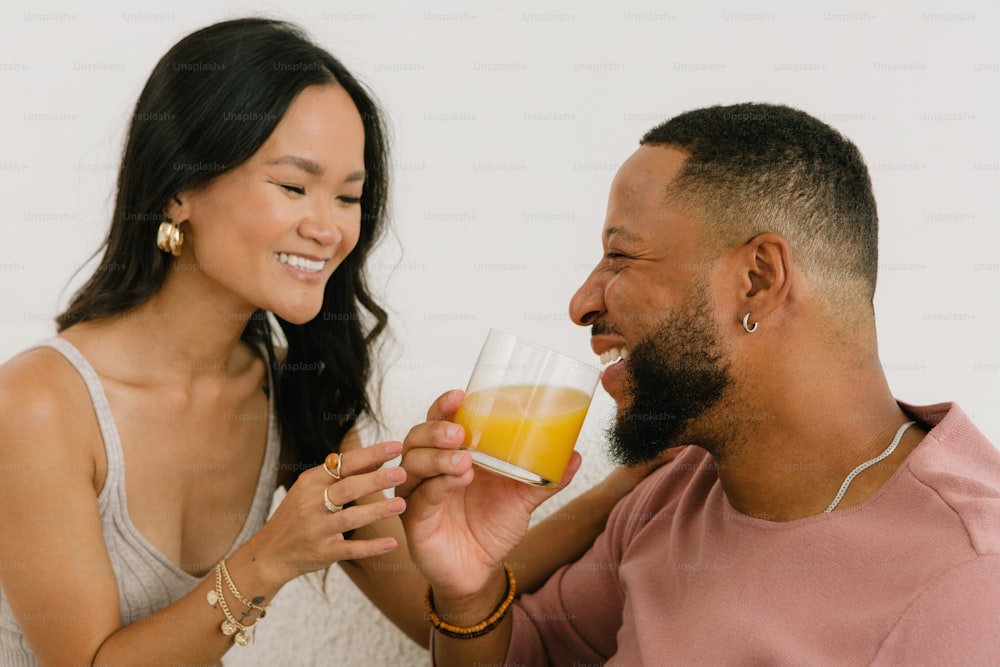 a man holding a glass of orange juice next to a woman