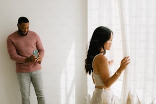 a man standing next to a woman holding a cell phone
