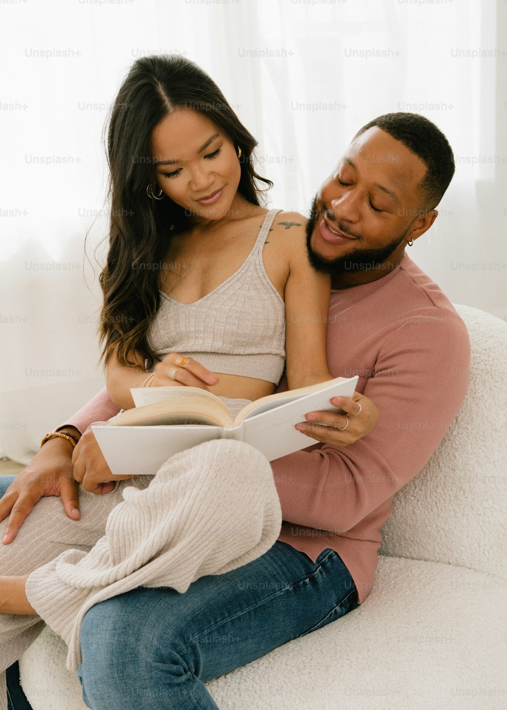 a man and woman sitting on a couch reading a book