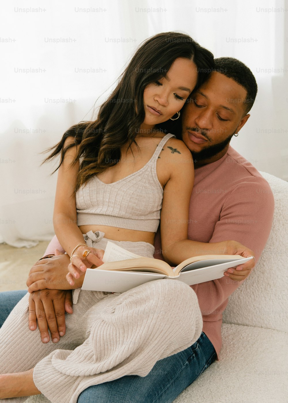 a man and woman sitting on a couch reading a book