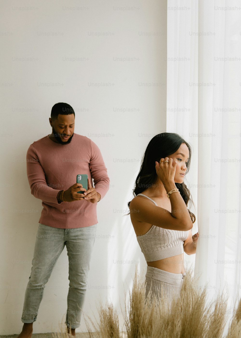 a man standing next to a woman holding a cell phone