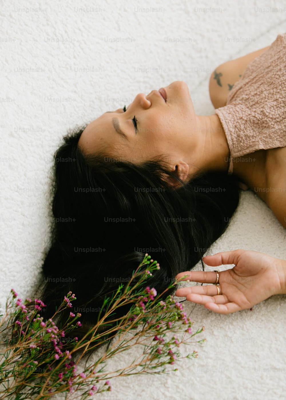 uma mulher deitada no chão ao lado de um ramo de flores