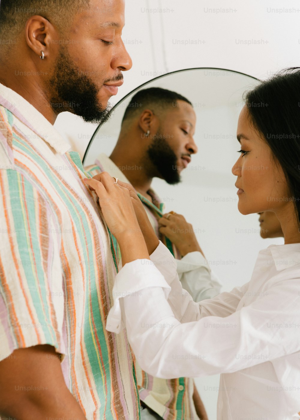 Un hombre ajustando la corbata de una mujer frente a un espejo
