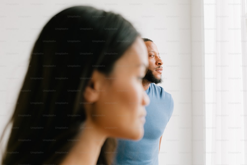 a man standing next to a woman in front of a window