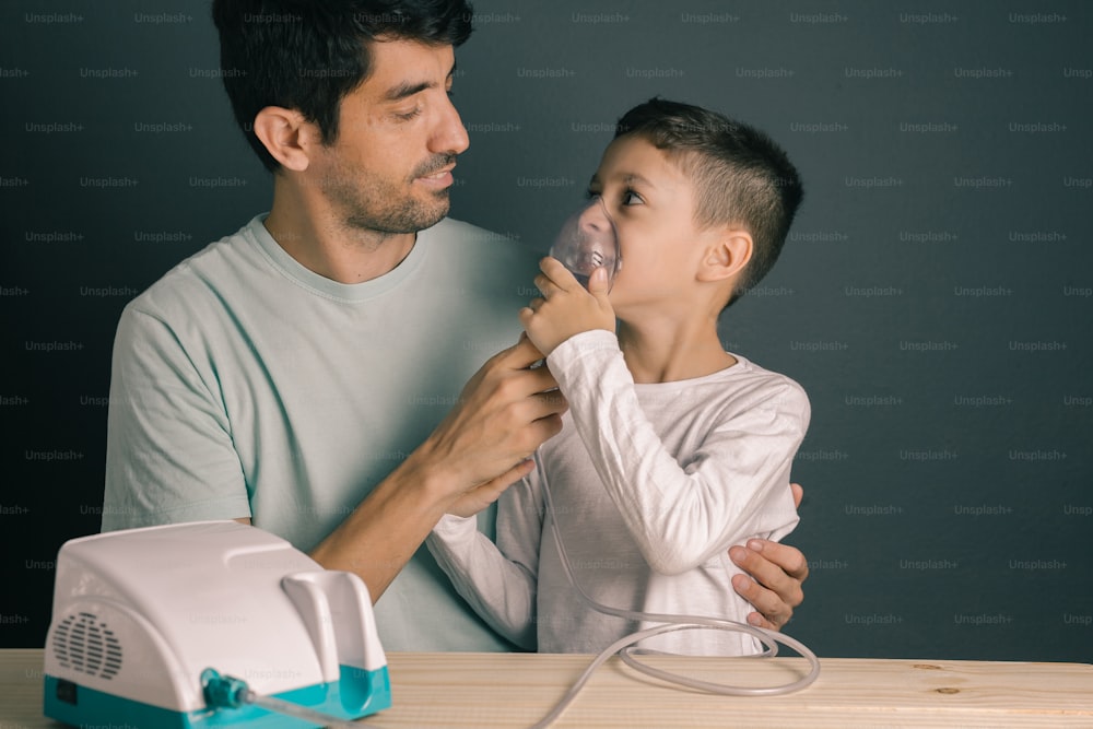 Retrato de pai e filho usando inalador doméstico / nebulizador
