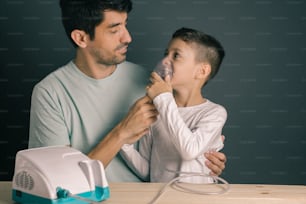 Retrato de padre e hijo usando inhalador/nebulizador doméstico