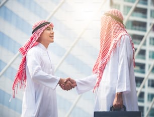 Belo empresário árabe, engenheiro / arquiteto apertando as mãos frente do projeto de construção de novas construções, união, trabalho em equipe, cooperação para o conceito de negócios