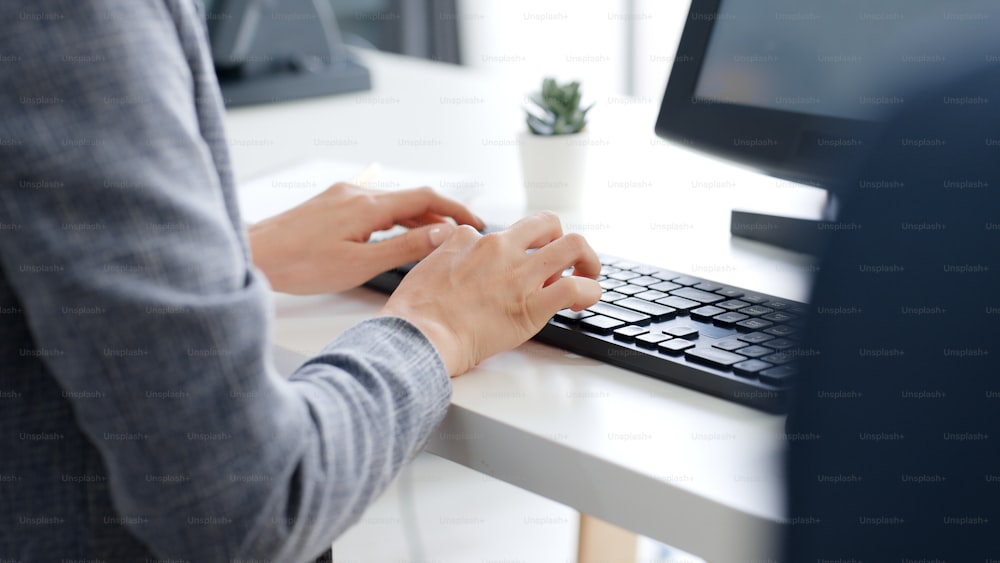 Primi piani uomini d'affari mani che digitano sulla tastiera computer desktop per l'utilizzo di internet, la ricerca di dati, il lavoro, la scrittura di e-mail.